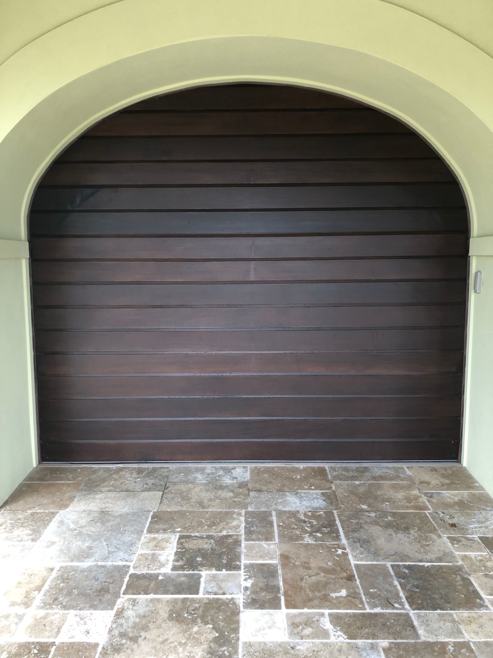 Dark wooden door set within an arched entryway; stone tile flooring.