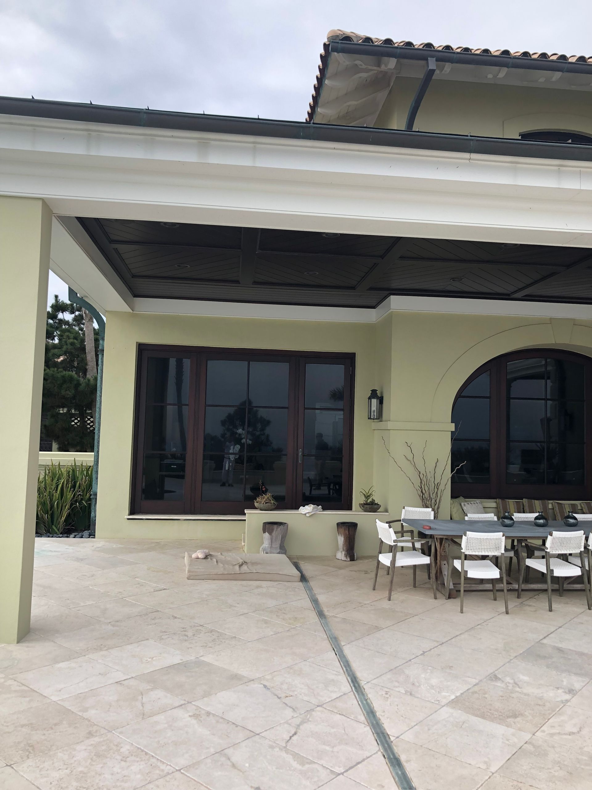Patio with tan tile, light green walls, brown doors and windows, and a dining table.