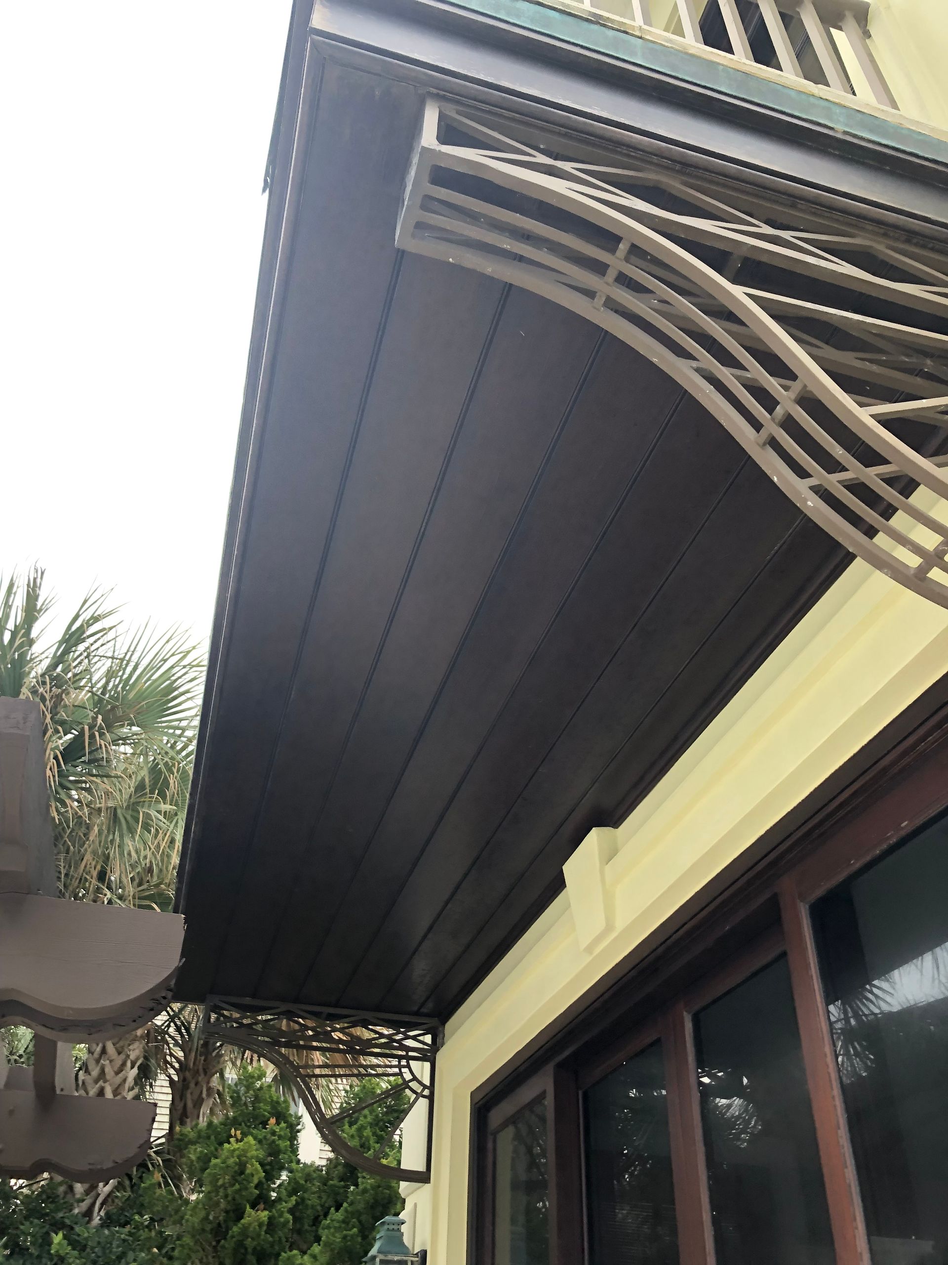 Brown awning on a building, with a window and a decorative brown structure on the right side.