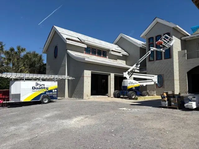 Construction site: crew working on a two-story building. Boom lift extends to windows. A trailer with the