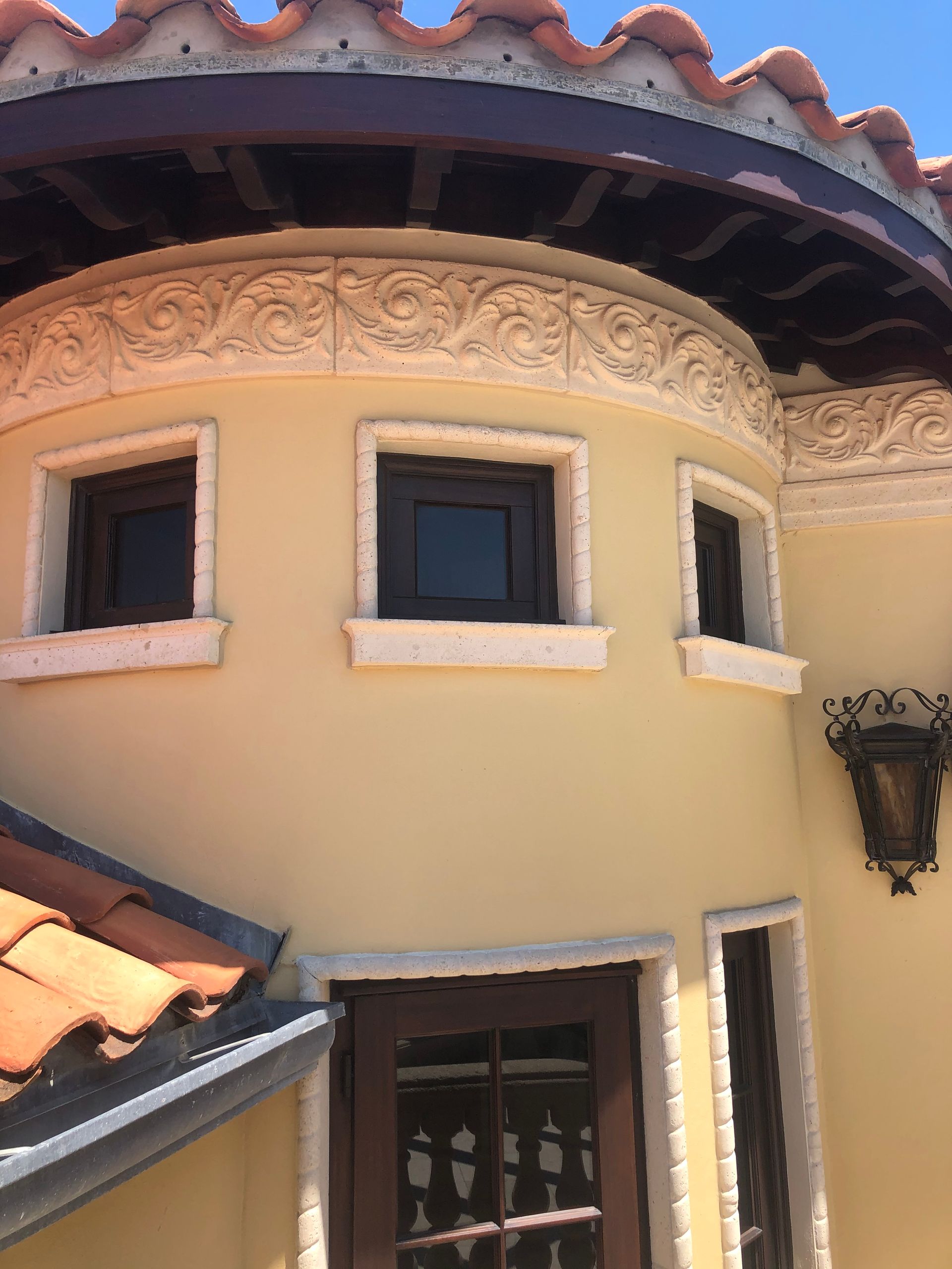 Tan stucco building with decorative trim, arched windows, and a terracotta tile roof.