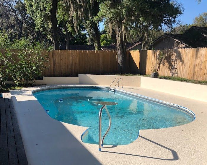 A large swimming pool with a wooden fence in the background