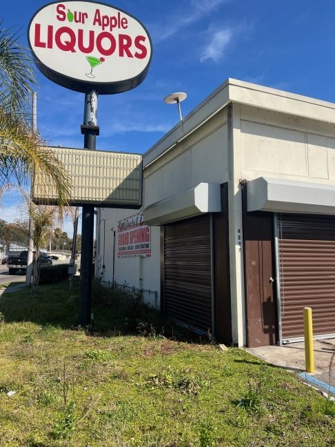 Sour Apple Liquors store exterior with closed security shutters and sign.