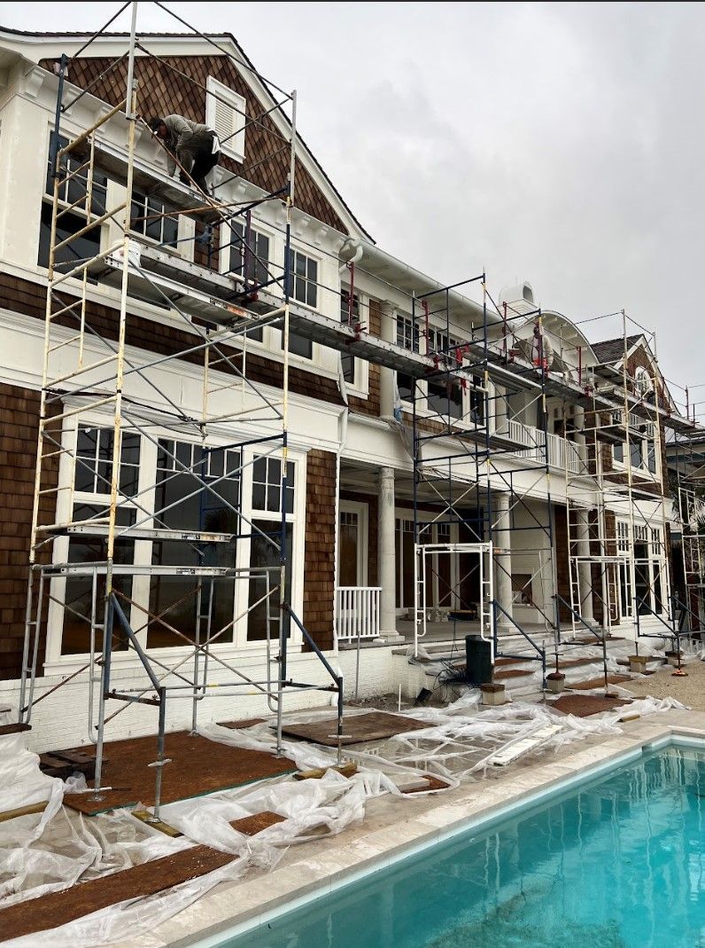 A large building with scaffolding around it and a pool in front of it.