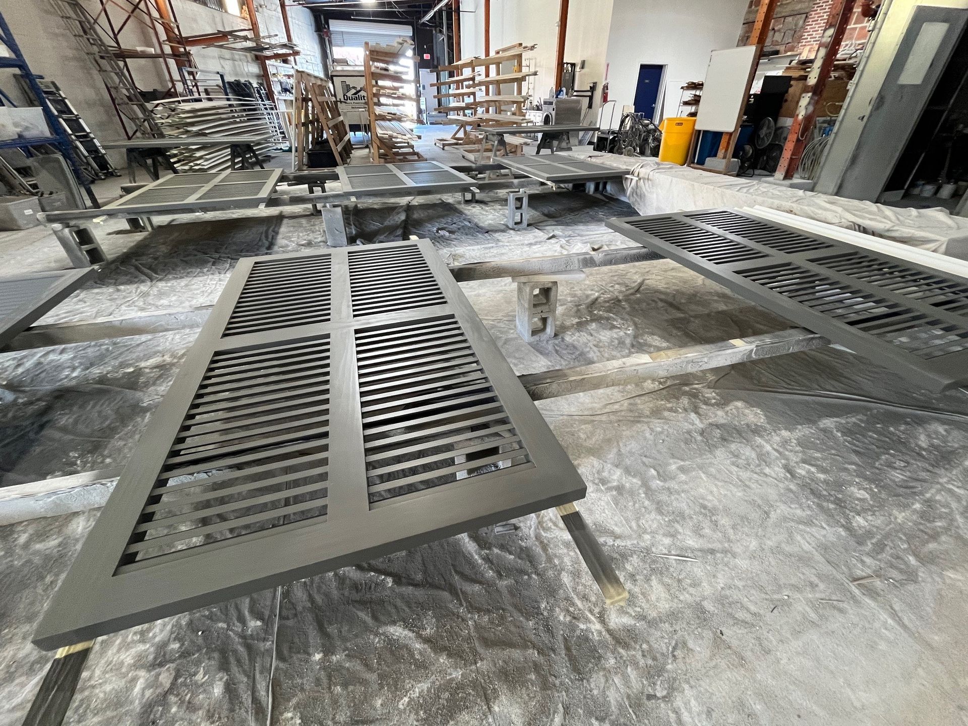Metal gates, recently painted gray, resting on supports in a workshop.