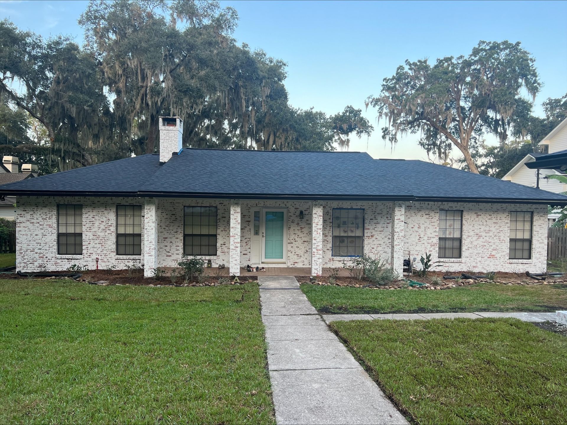 A white brick house with a blue roof and a blue door