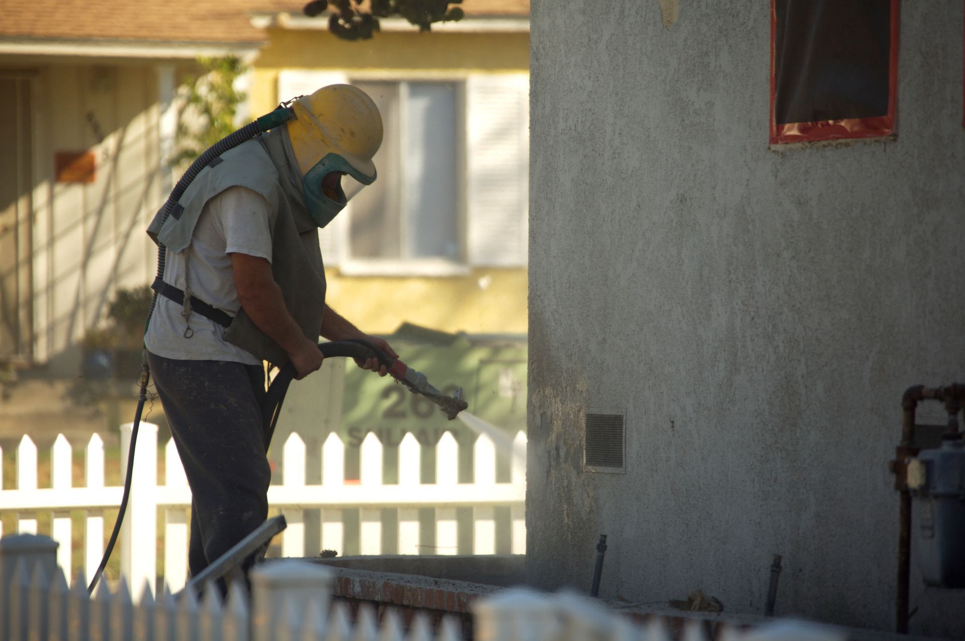 A man wearing a mask is sandblasting a wall.