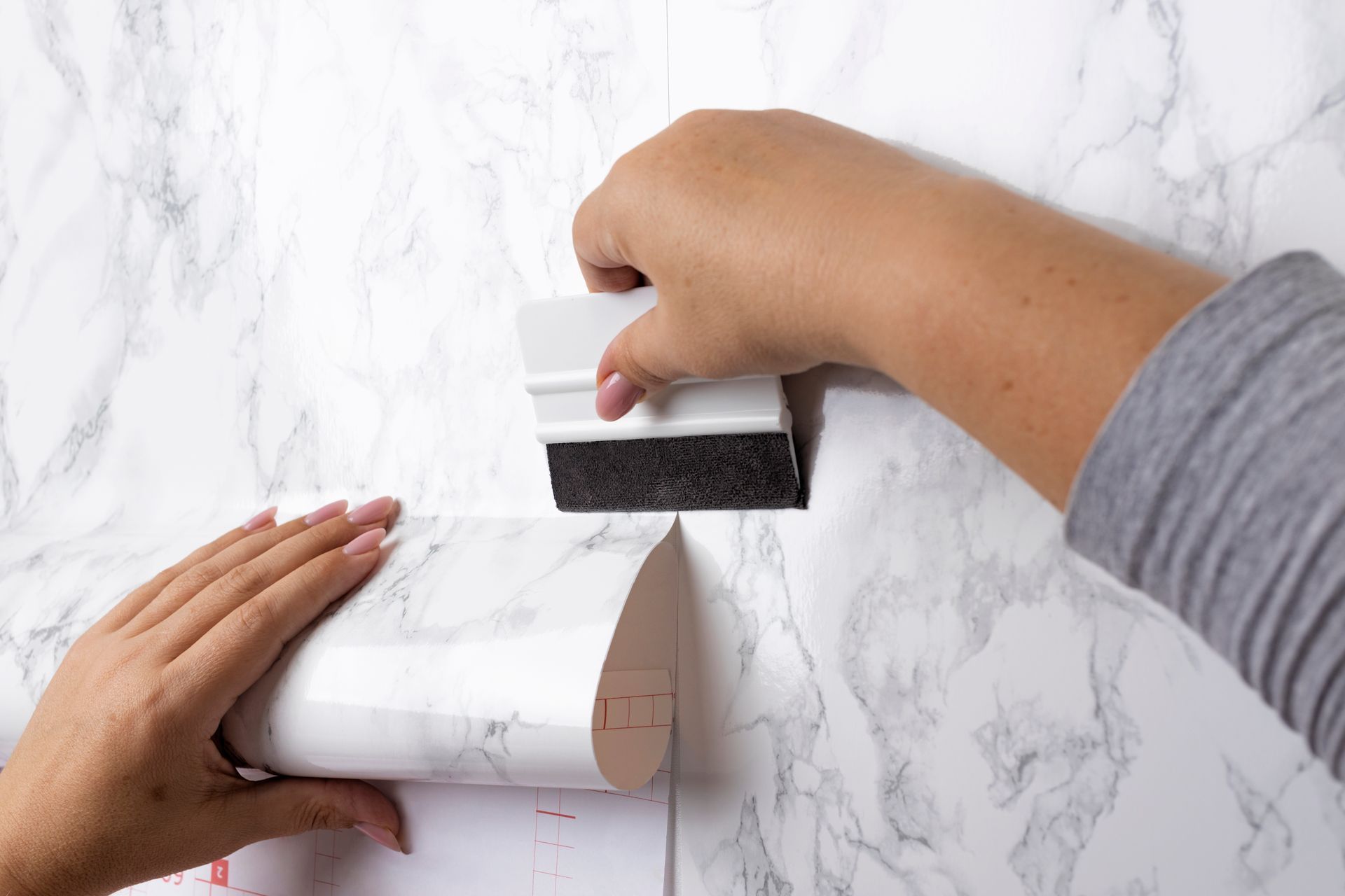 A person is using a sponge to apply marble paper to a wall.