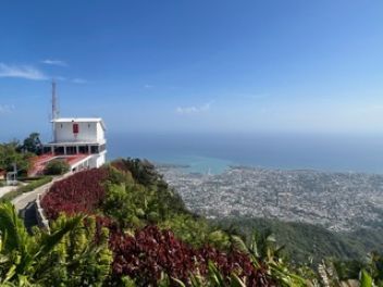Scenic view of a city on the coast from a mountaintop with a building and blue sky.