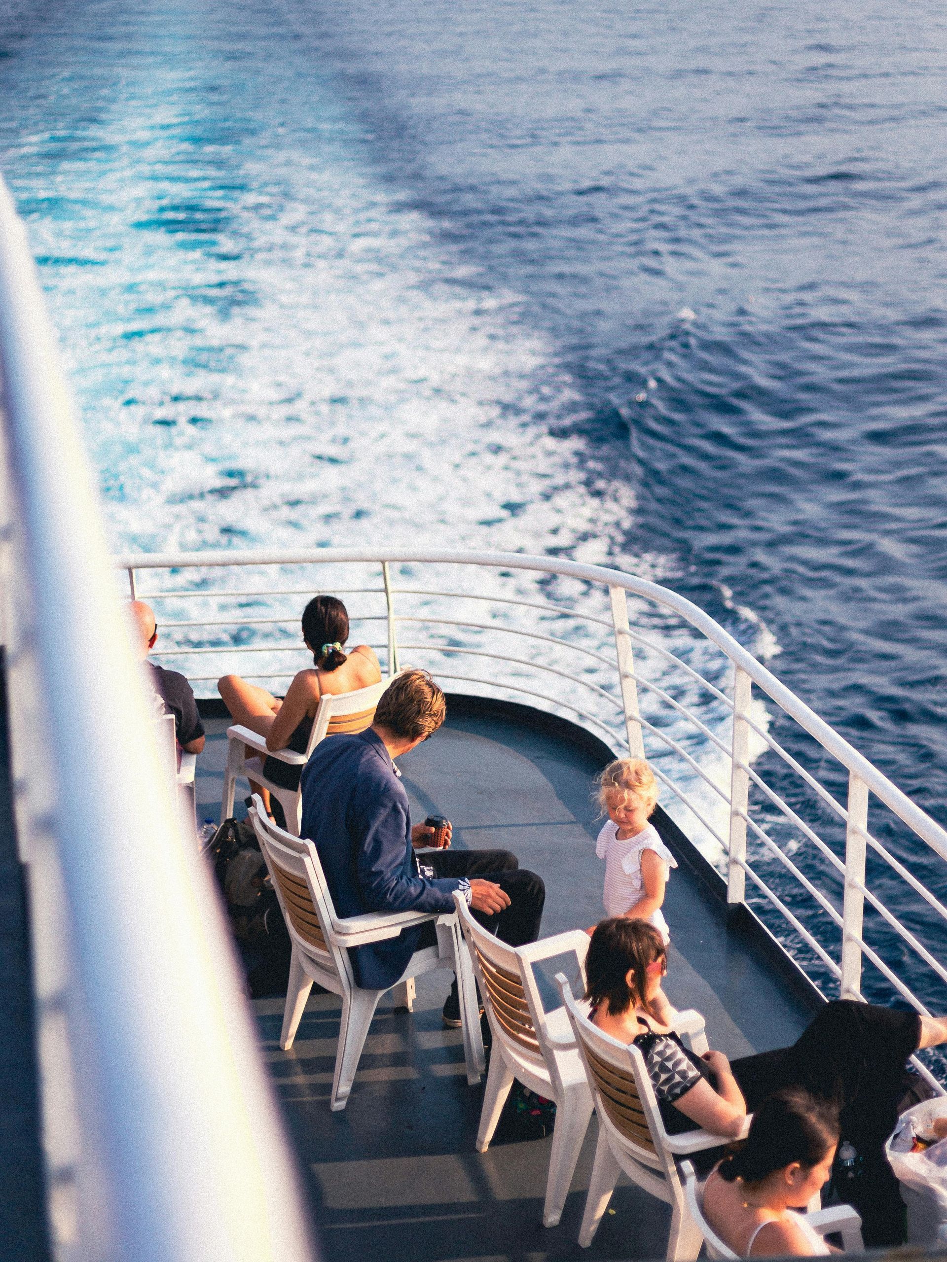 People on a Caribbean cruise on the ocean watching the wake trail behind the boat. 