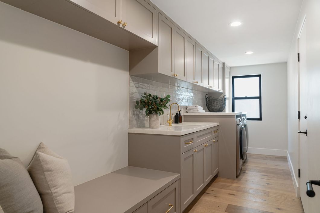 A laundry room with a bench and a washer and dryer.