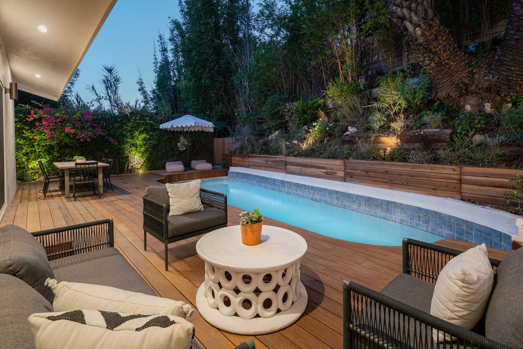 There is a large swimming pool in the backyard of a house.