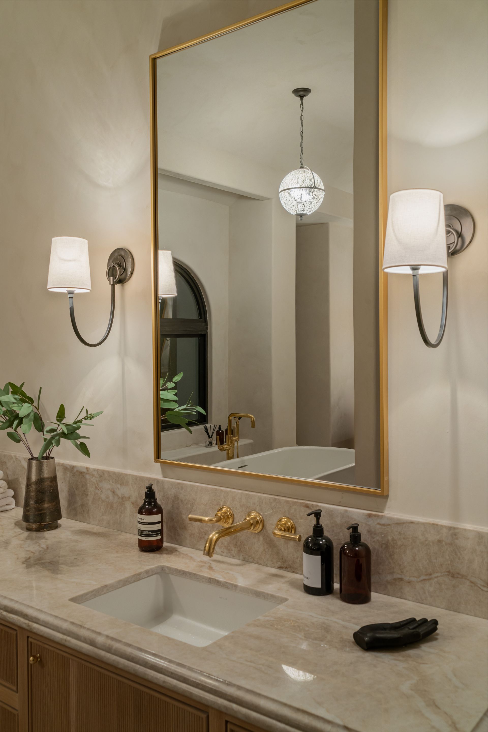 A bathroom with a sink , mirror and two lights.