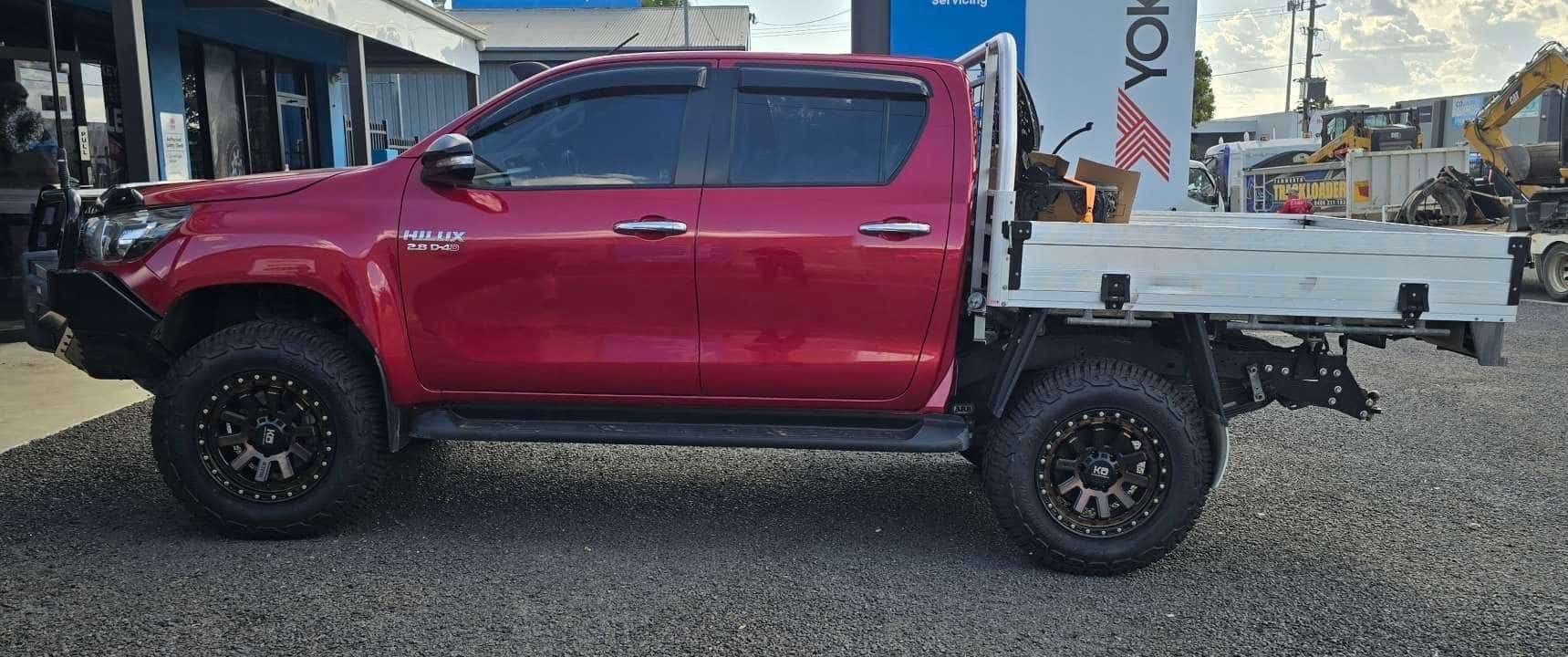 A Red Truck With A White Tray On The Back Is Parked In A Gravel Lot — Smitty's Tyres & More In Taminda, NSW