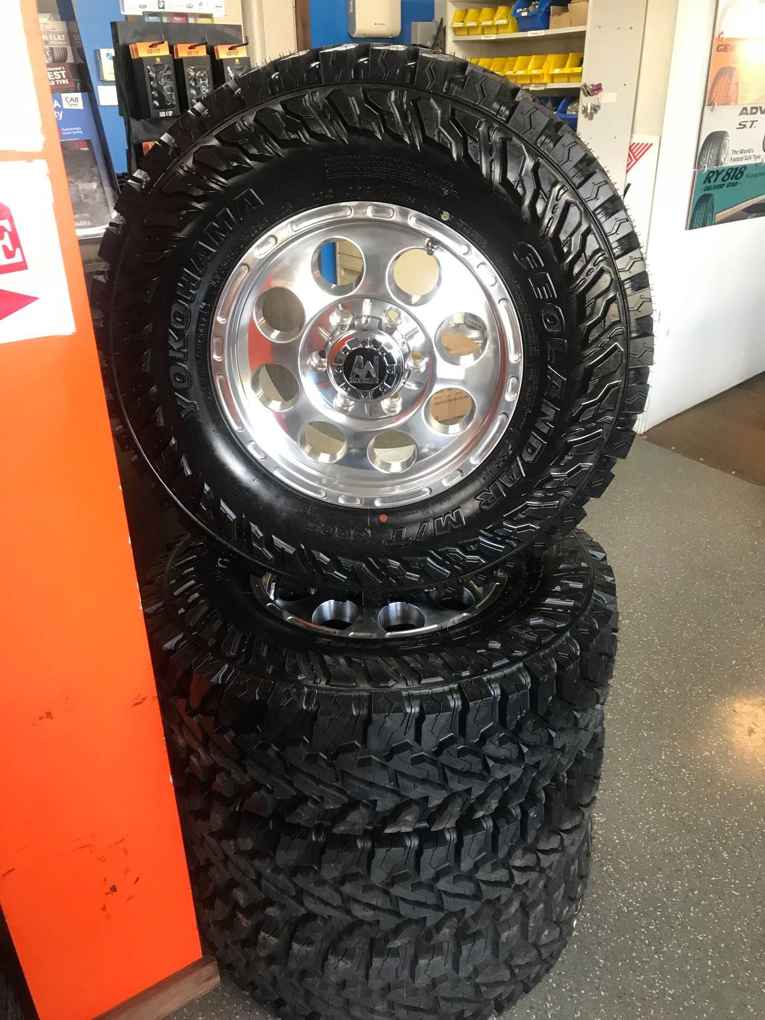 A Stack Of Tires And Wheels Are Sitting On Top Of Each Other In A Store — Smitty's Tyres & More In Taminda, NSW