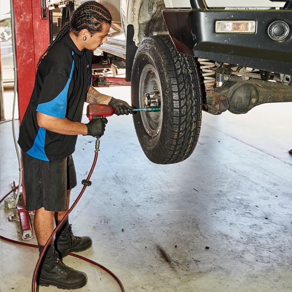 A Man Is Working on A Tire in A Garage — Smitty's Tyres & More In Gunnedah, NSW