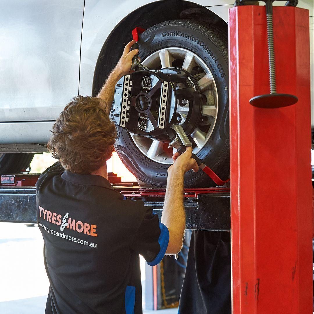 A Man in A Black Shirt that Says Tyres & More Is Working on A Car — Smitty's Tyres & More In Wlacha, NSW