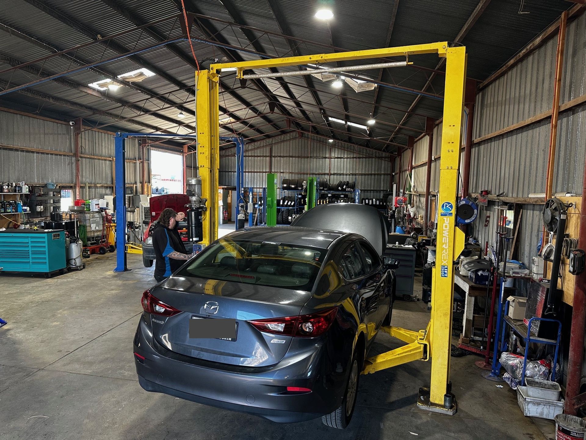 A Car Is Sitting On A Lift In A Garage — Smitty's Tyres & More In Taminda, NSW