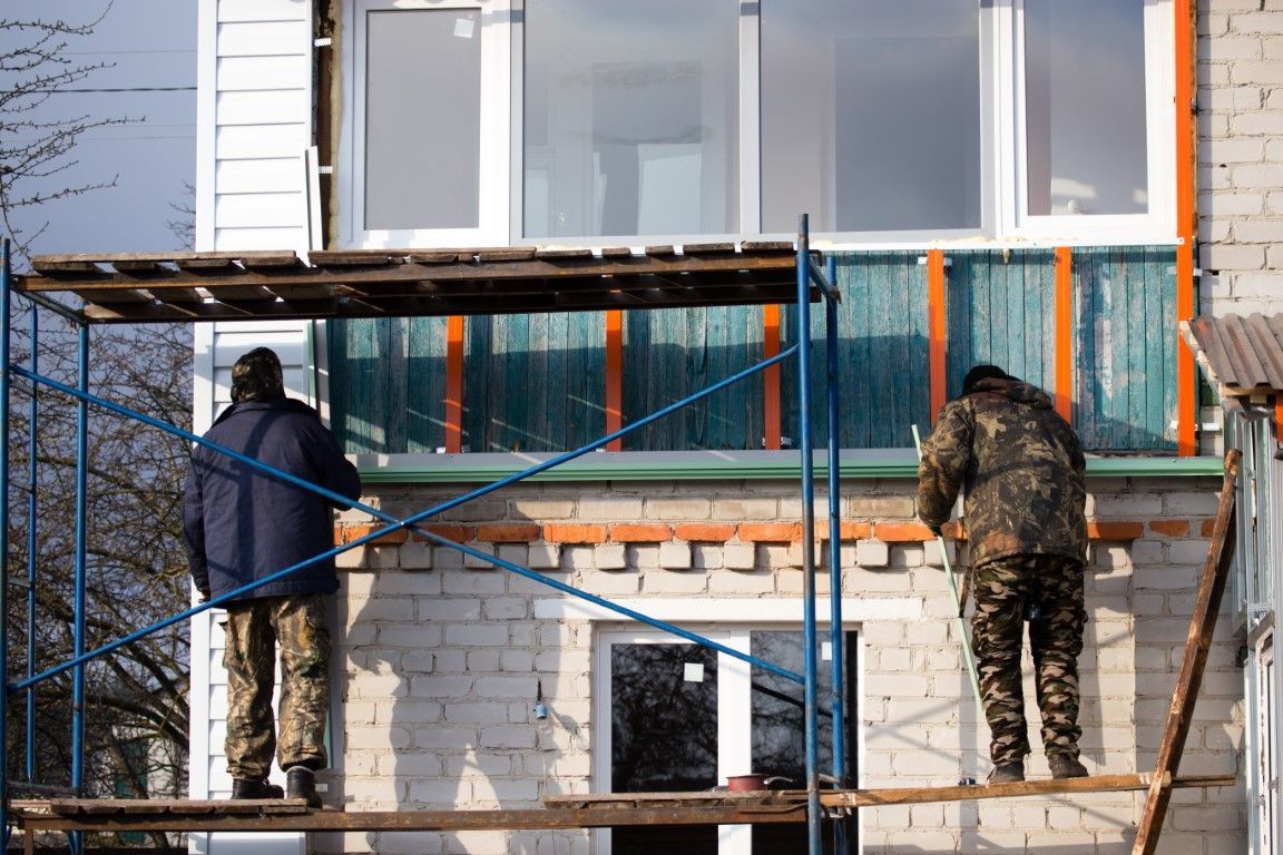 Image of two people working on the exterior of a home