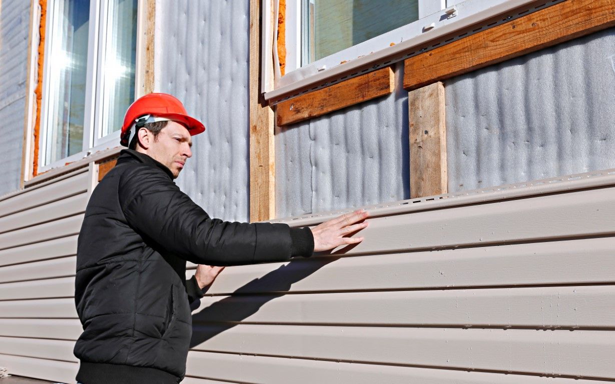 Man in a red hat installing new siding