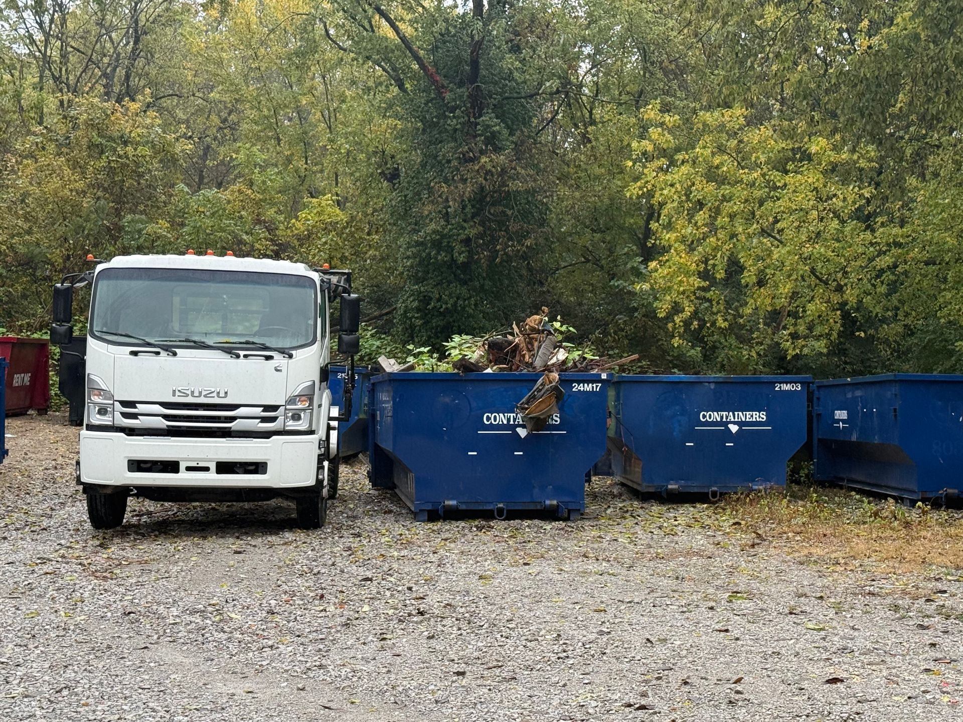 Large white dumpster filled with debris, parked on a brick patio. Red and white diagonal stripes on side.