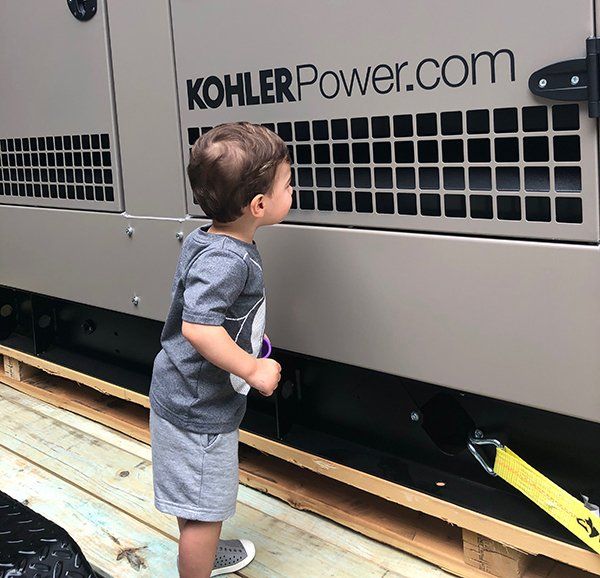 Child in Front of a Kohler Generator Installed by GenSpring Power, Inc. in Georgia.