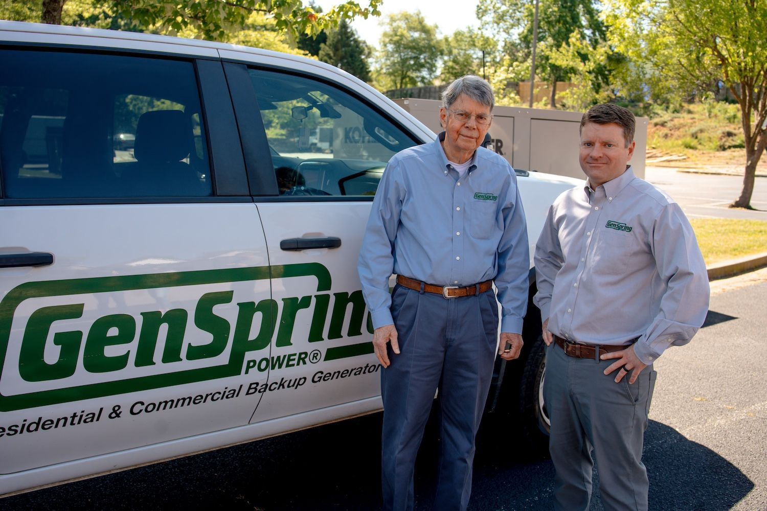 Two men standing beside a GenSpring Homes service van in a sunny parking lot