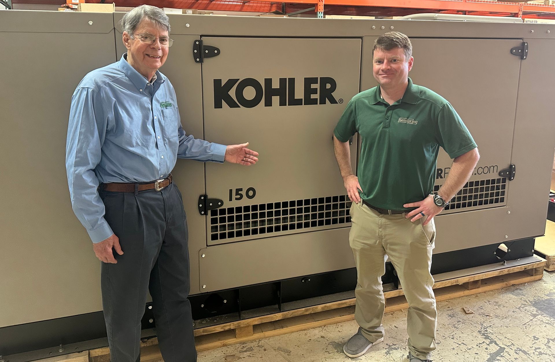 Two men standing beside a large Kohler generator in an indoor industrial setting.