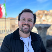 Um homem com barba e óculos está sorrindo para a câmera.