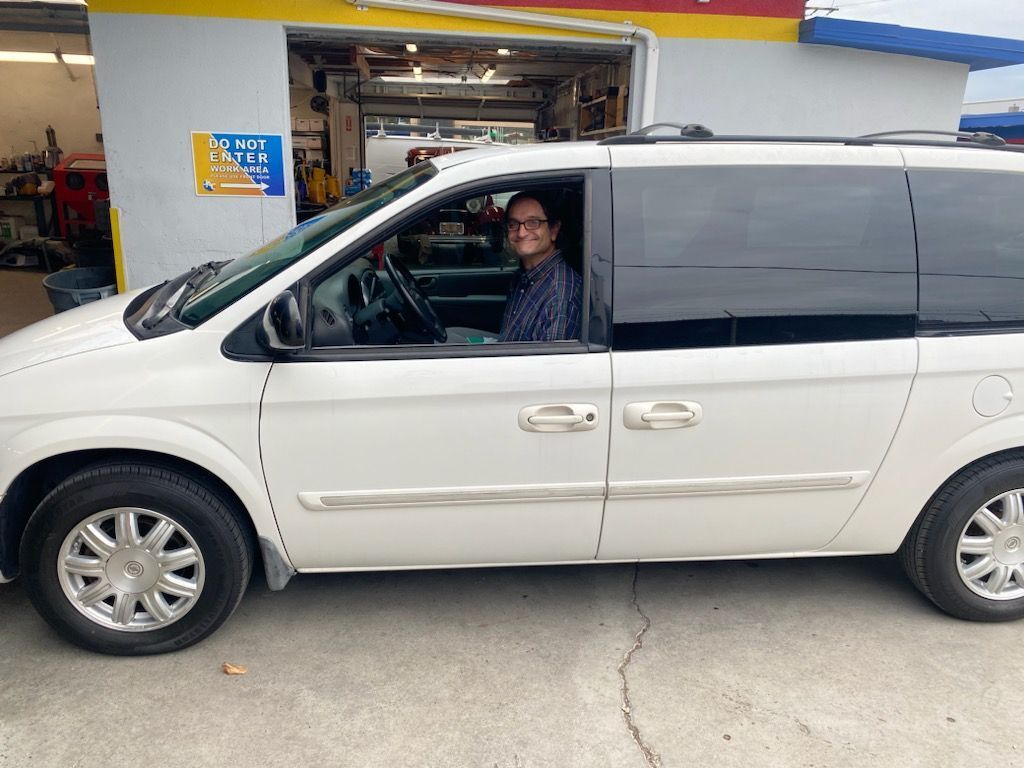 Person in a white minivan at a car service station.