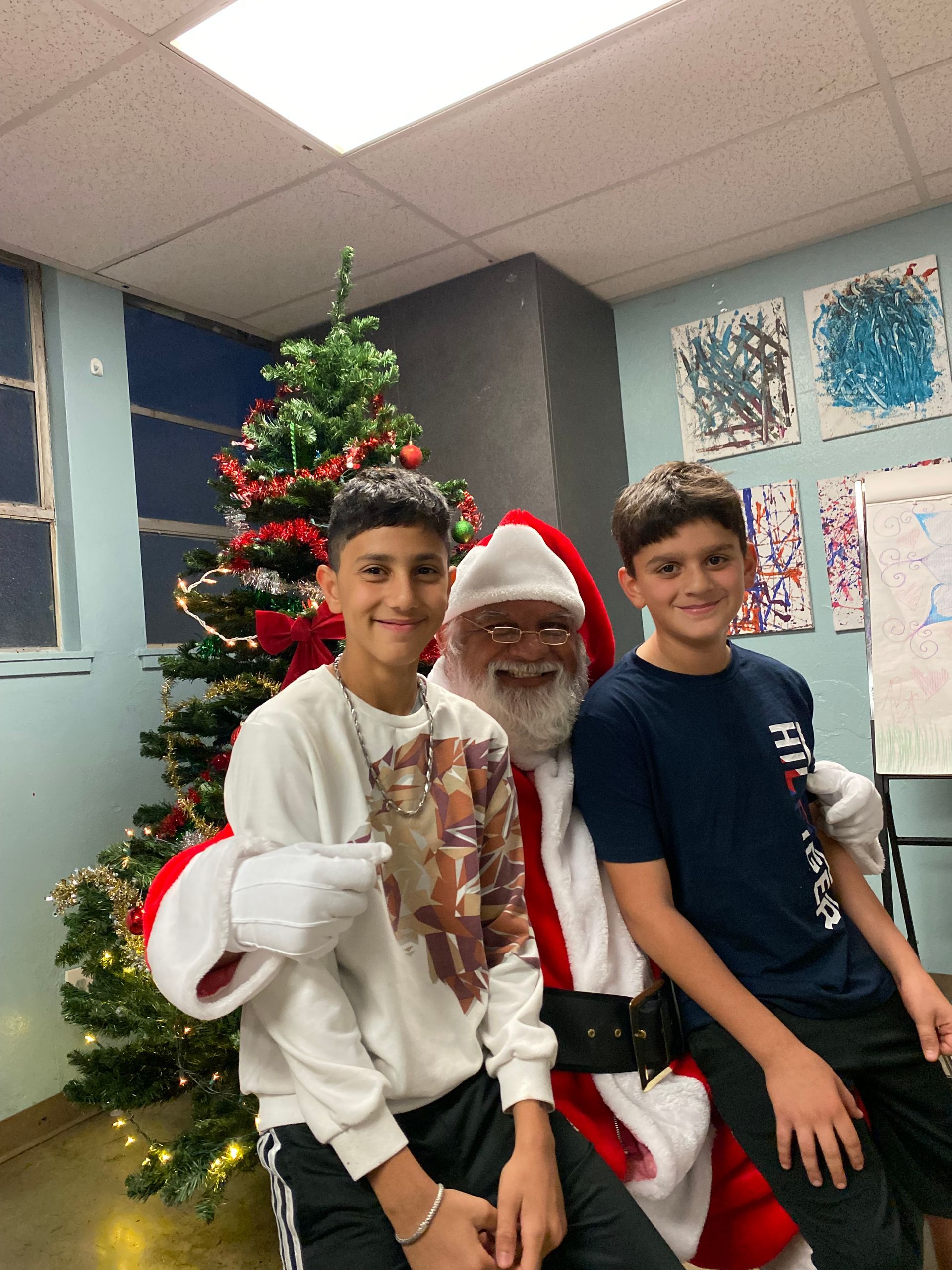 Two boys pose with Santa Claus in front of a Christmas tree.