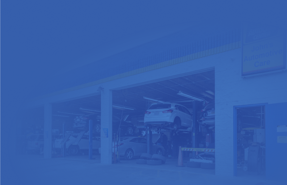 A car repair shop with vehicles on lifts, viewed from the outside.