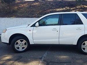 White Saturn SUV parked next to a wall.