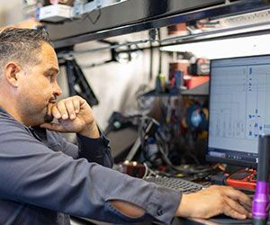 Man at computer, analyzing diagrams in a repair shop.