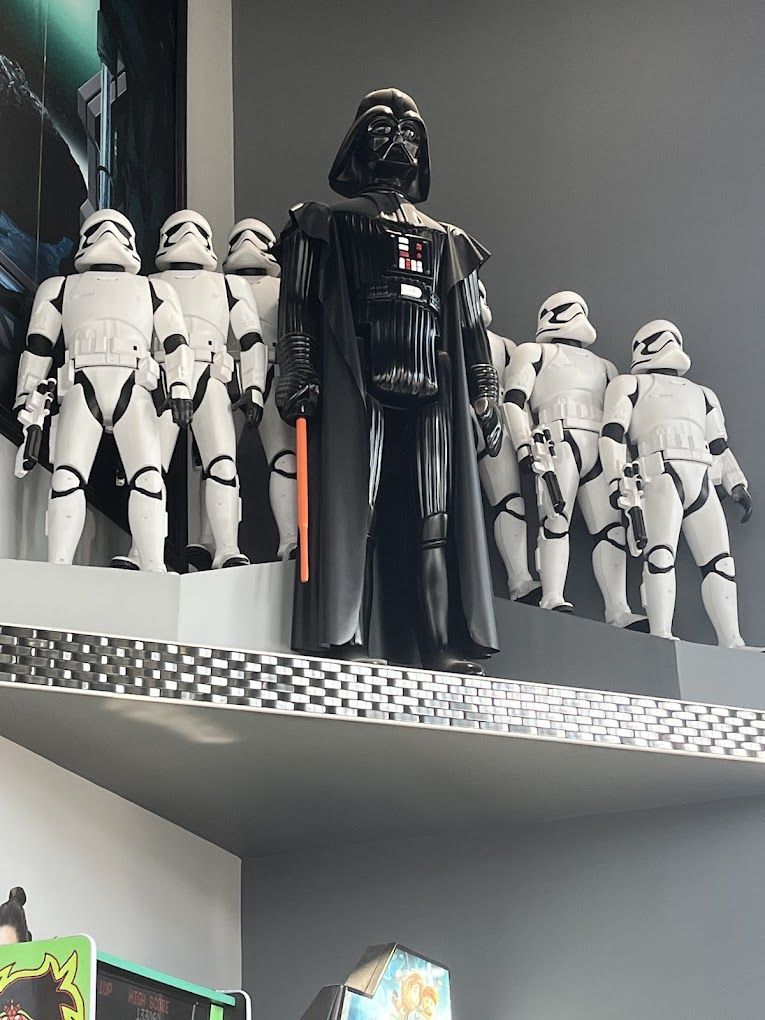 Darth Vader and several Stormtroopers statues on a shelf, inside a room.