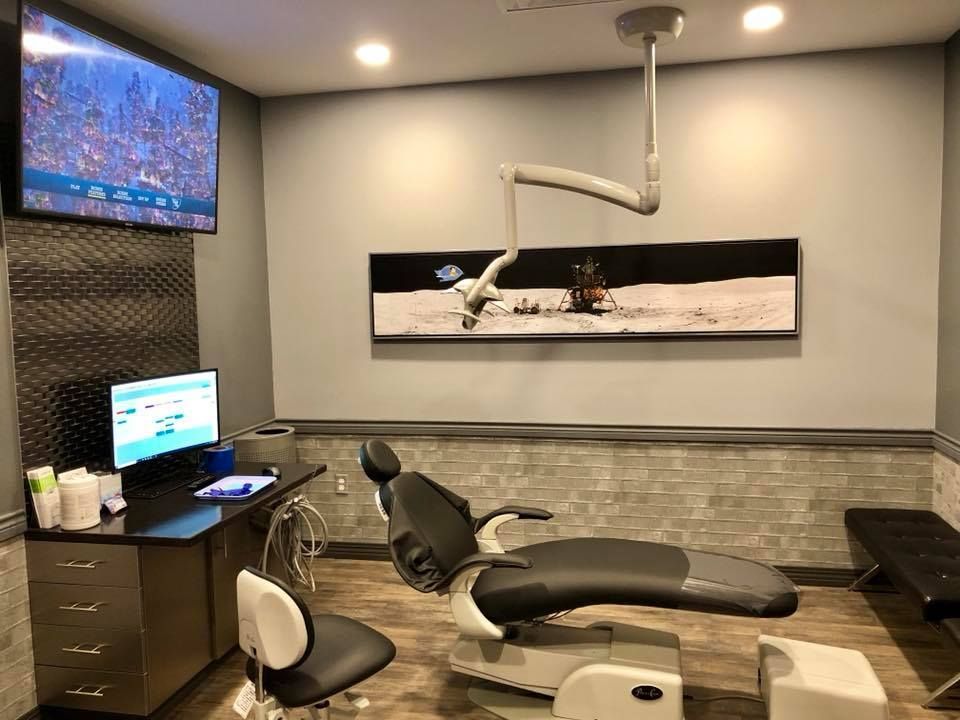 Dental office with chair, computer, and space-themed artwork.