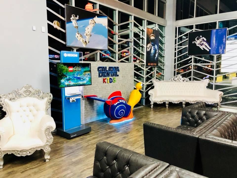 Dental office waiting area: blue, white, and black decor, children's play area, and decorative seating.