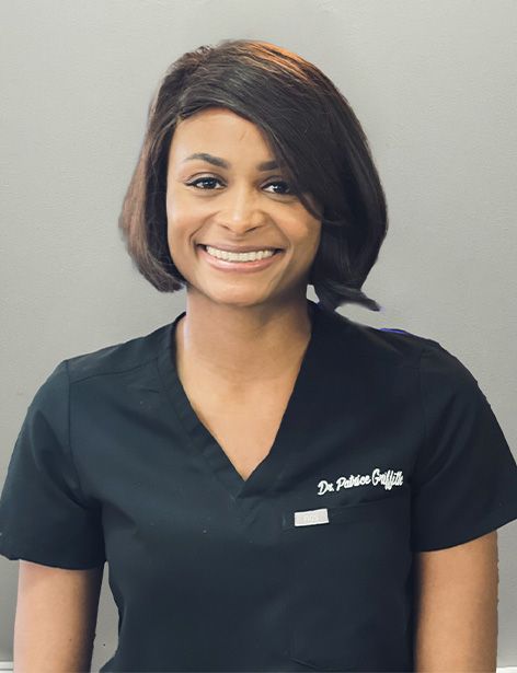 Smiling Black woman in black scrubs, possibly a healthcare professional.