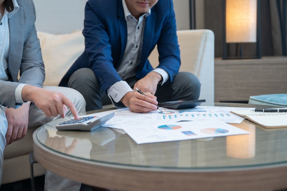 Two people in business attire reviewing charts and notes at a glass conference table