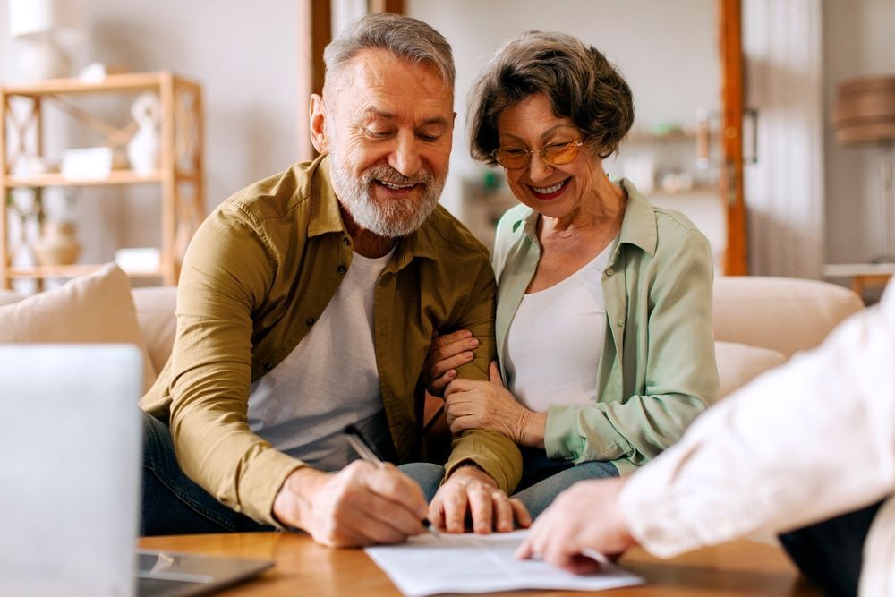 Smiling couple reviewing documents together at a table in a bright home office