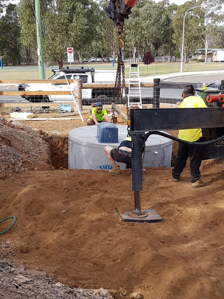 a crane is lifting a concrete cylinder into a hole .
