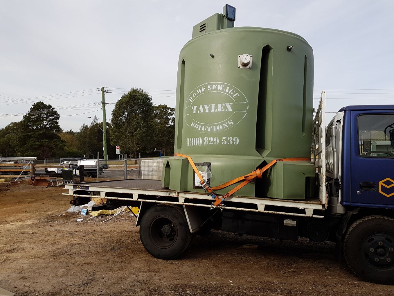 a large green tank is on the back of a truck .