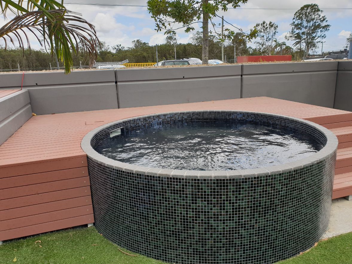 a round hot tub with a wooden deck and stairs in a backyard .