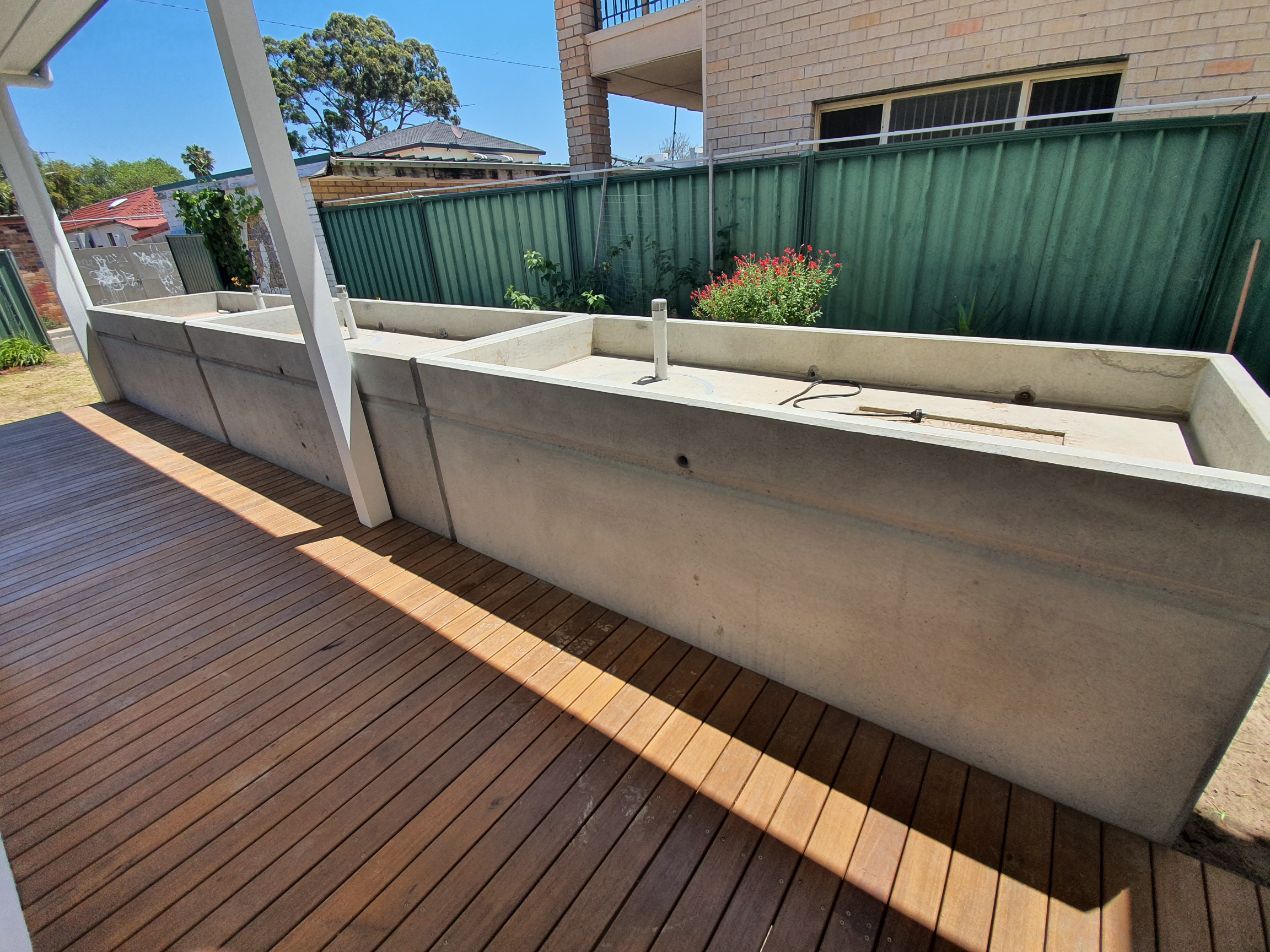 a wooden deck with a concrete wall and planters on it .