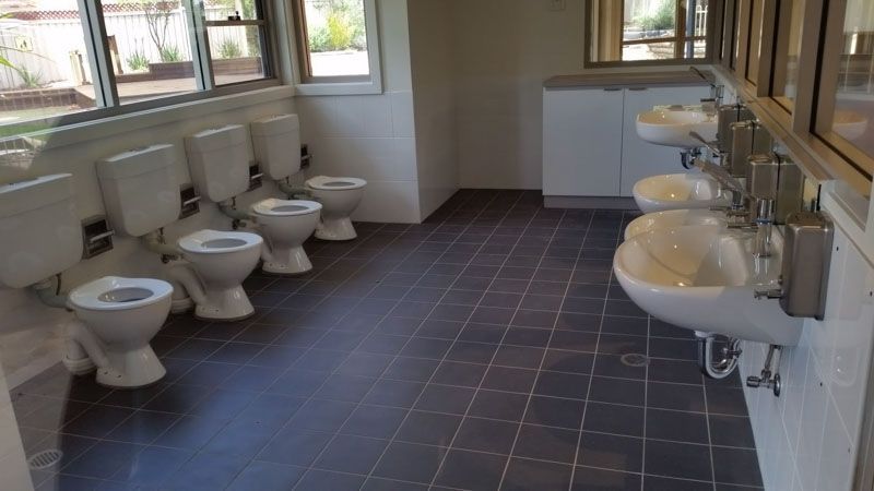 a bathroom with a row of toilets and sinks