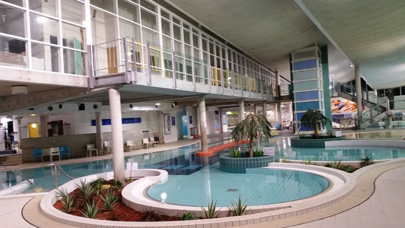 a large indoor swimming pool with a slide in a building .