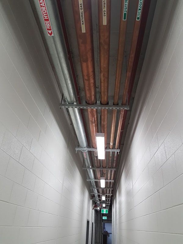 a long hallway with copper pipes hanging from the ceiling .