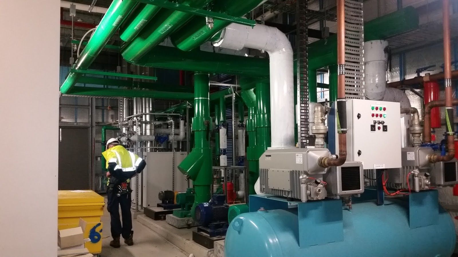 a man is standing in a room with a lot of pipes and machinery .