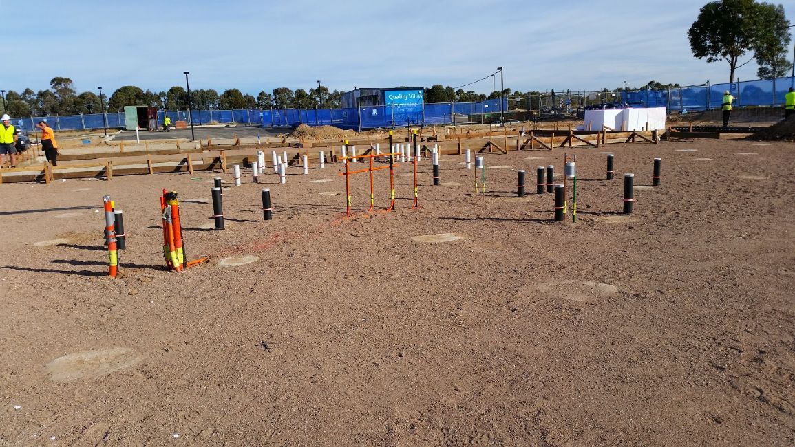 a group of construction workers are standing in a dirt field .