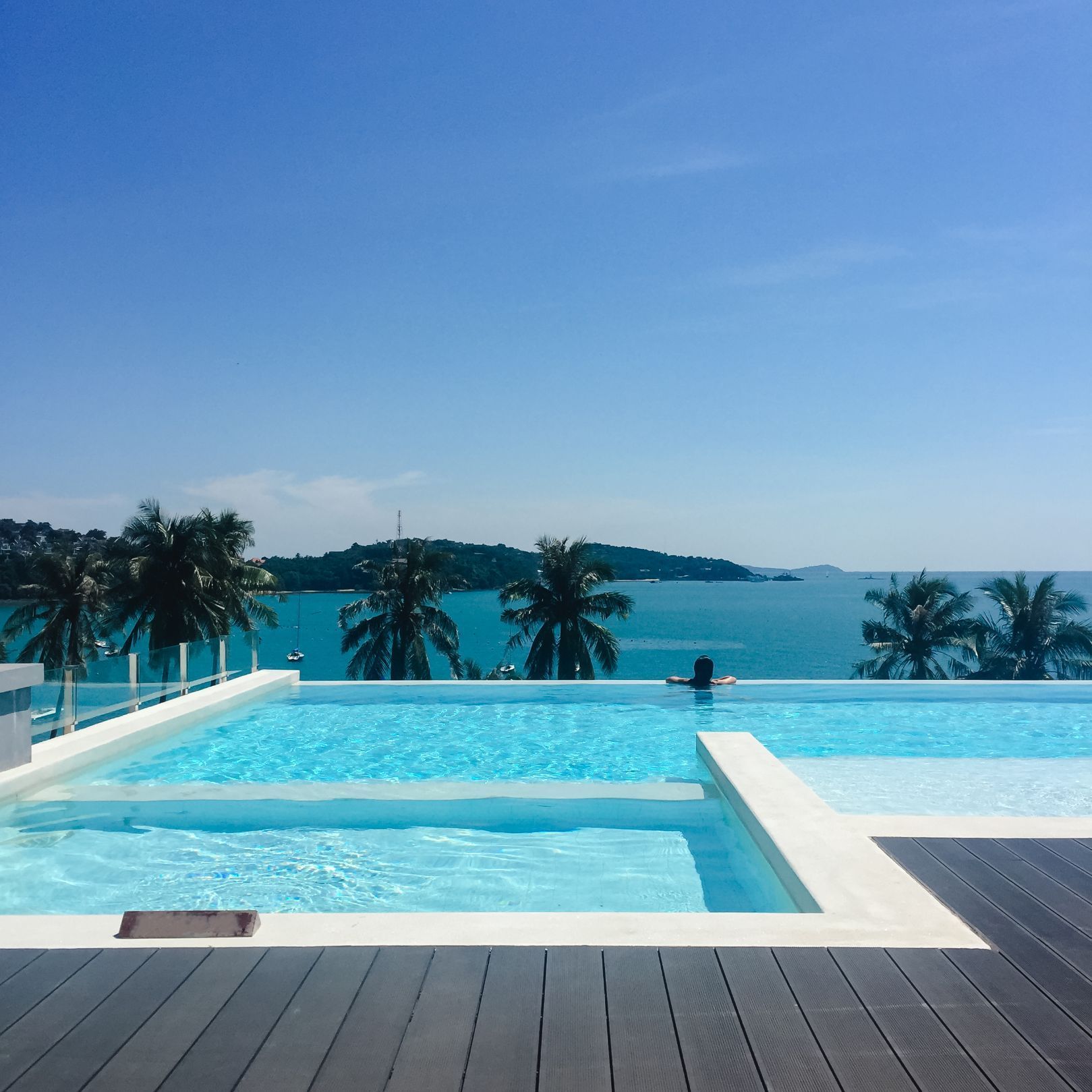 a swimming pool with a view of the ocean and palm trees